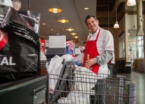 Opportunity House client smiles at the camera while working at his job at a grocery store.