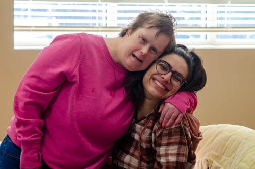 An employee and a resident share a happy moment, smiling and expressing affection. Opportunity House provides 24-hour residential care.