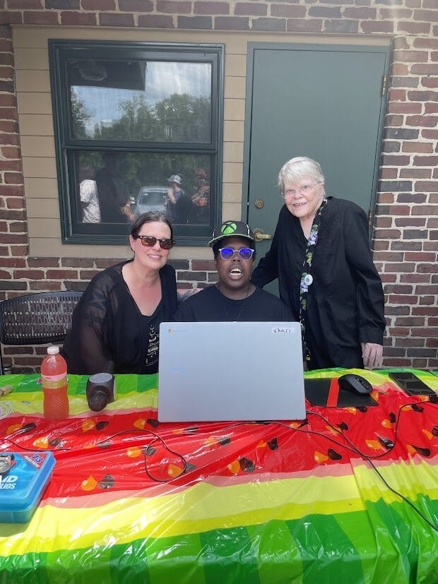 OH client and attendees sit behind a table and smile while working at the Watermelon Explosion gathering.