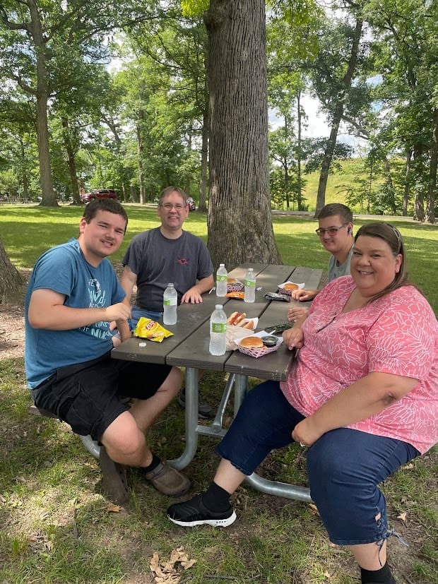 Community members and cients sitting outside at a picnic table enjoying Opportunity House’s Watermelon Explosion event.