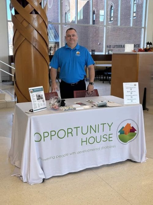 Opportunity House employee staffing a booth at a college job fair.