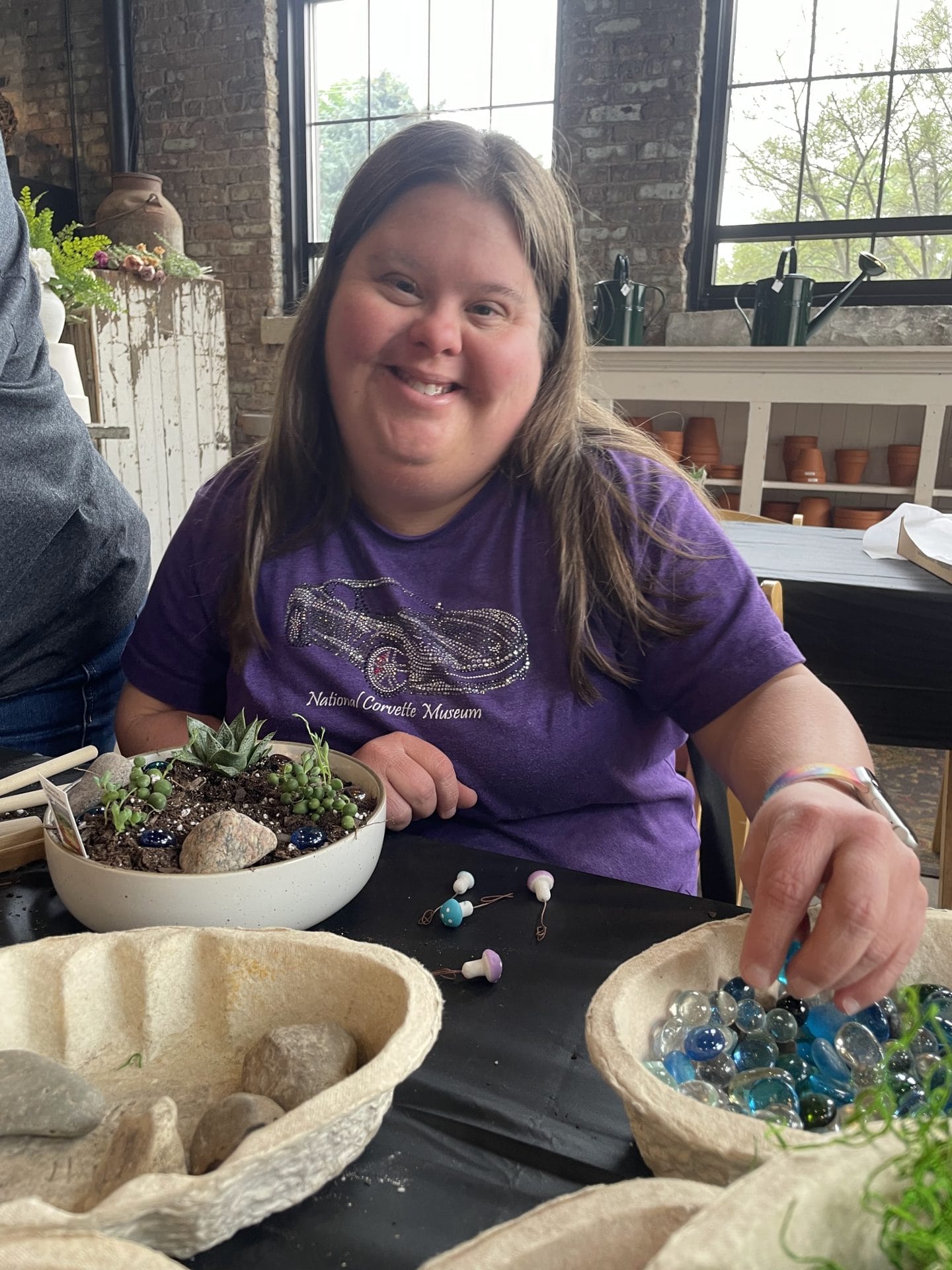 Opportunity House Recreation client smiling at camera while doing craft.