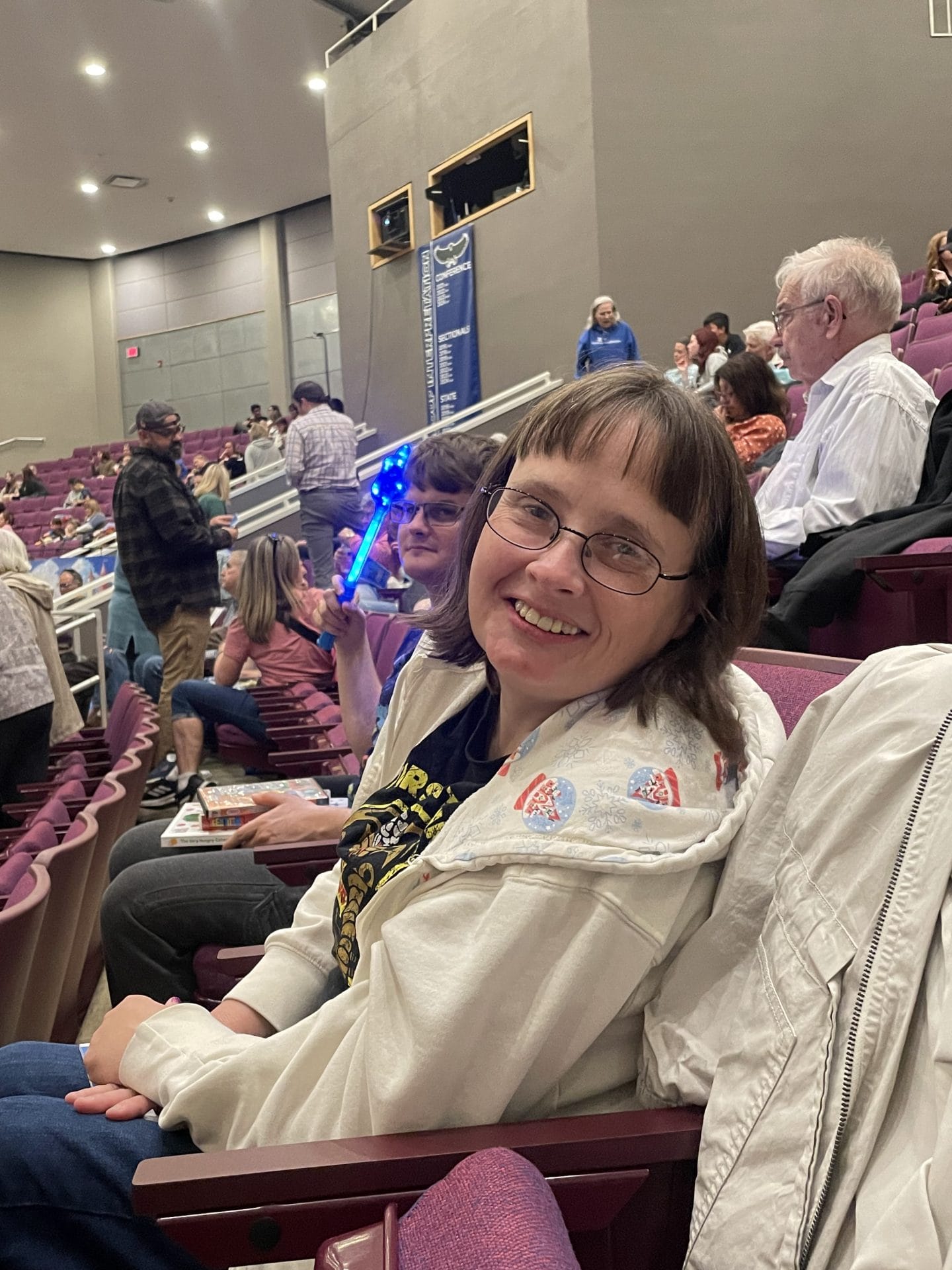 Opportunity House Recreation client smiling for photo in a movie theatre chair.