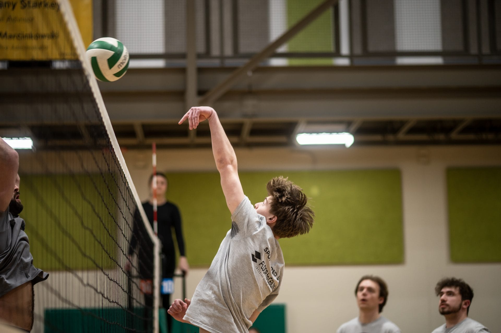 Player spiking ball over net.