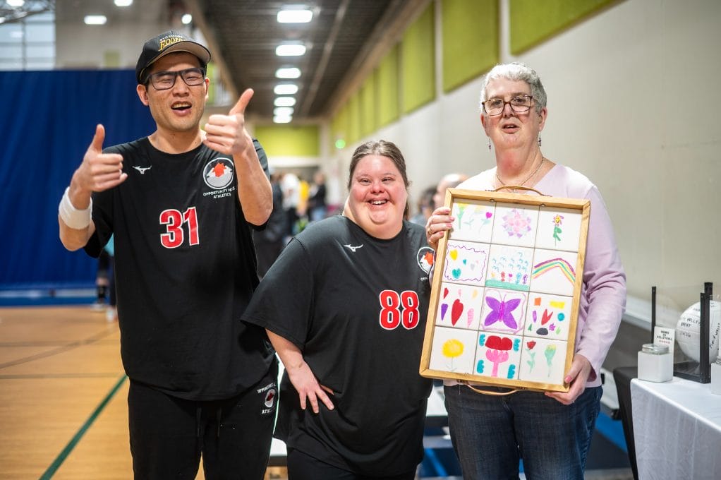 Three Opportunity House clients showcasing Recreation tile designed tray raffle item.