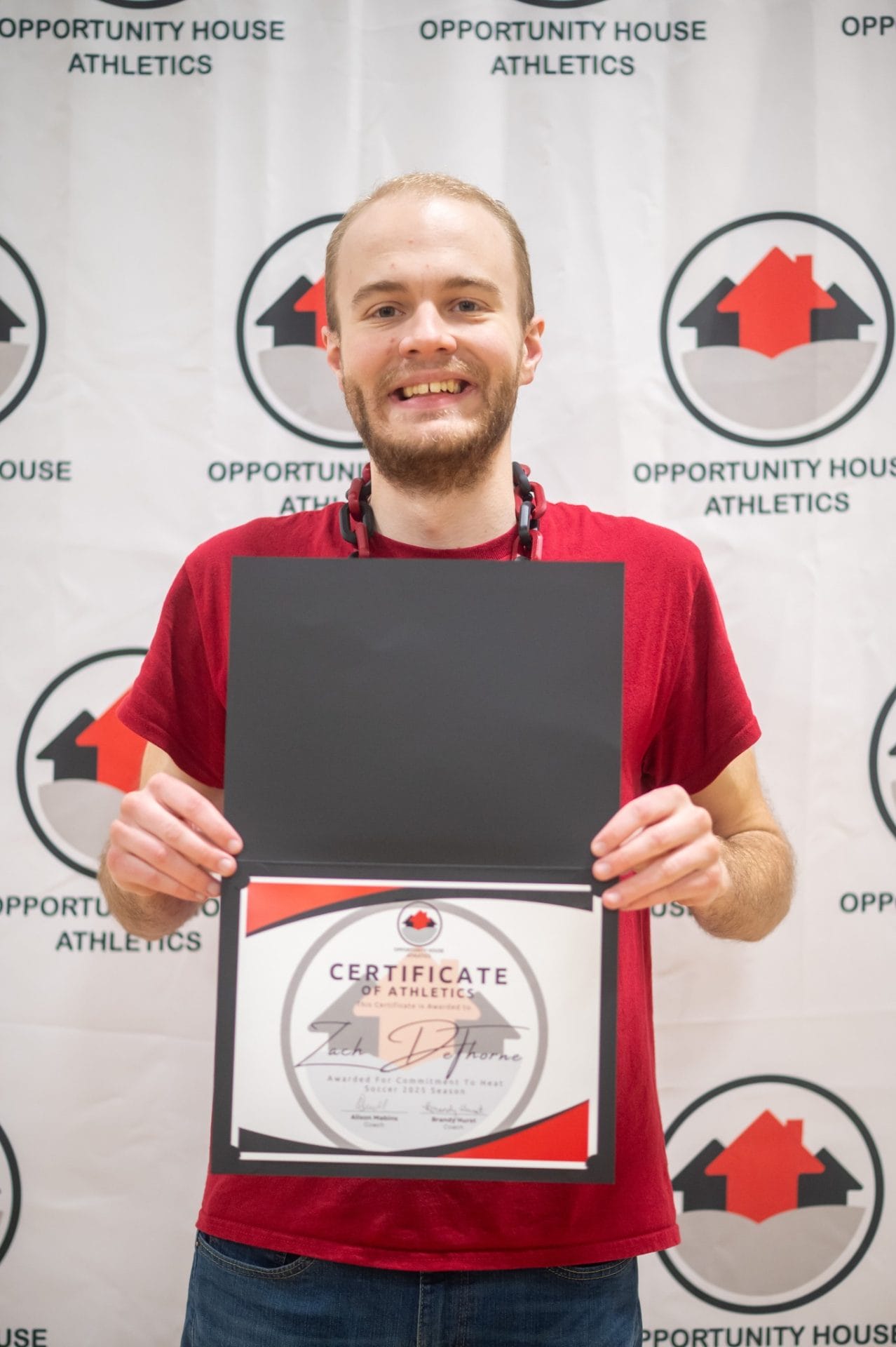 Opportunity House Athletics athlete holding certificate