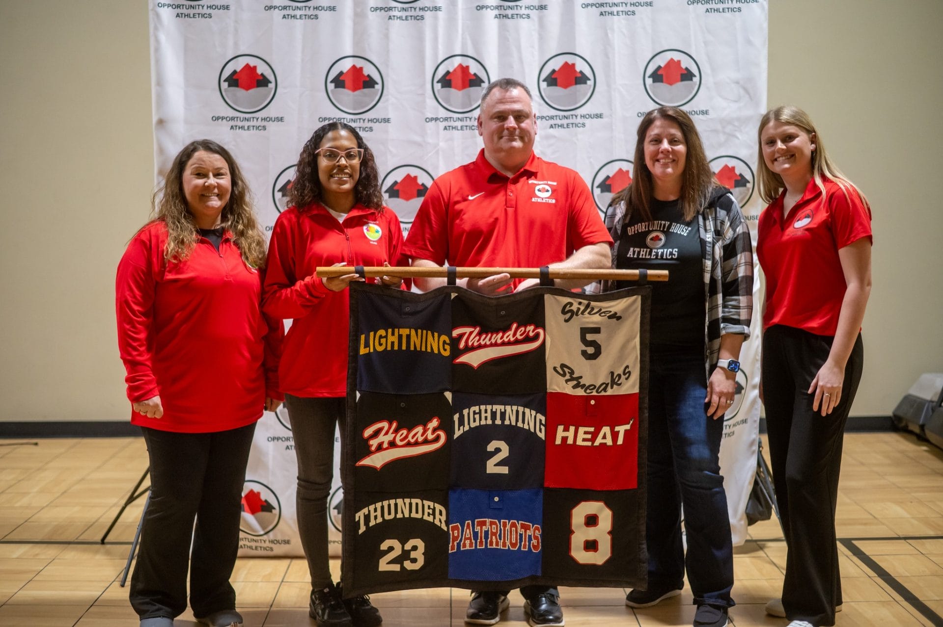 4 Opportunity House Athletics coaches with Opportunity House Athletics Coordinator holding custom quilt